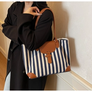 Detail shot of large navy striped tote bag with brown leather accents on a model