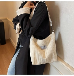 Détail du cabas en toile crème avec texture plissée et large bandoulière à motif losanges