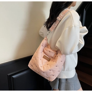 Détail d'un sac à bandoulière rose matelassé avec broderie nœud et sangle