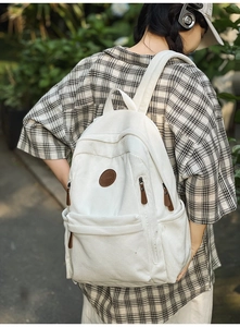 Detailed texture of white corduroy backpack with leather logo and sturdy zippers