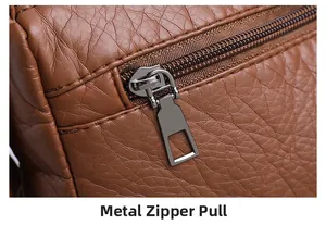 Macro shot of gunmetal hardware zipper pull on brown lychee texture leather bag