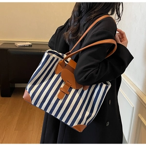 Detail of blue and white striped canvas tote with brown leather straps and trim