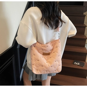 Détail du sac cabas rose matelassé avec broderie nœud et écusson en cuir