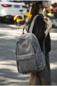 Detail of grey corduroy backpack showing texture and brown leather round brand logo