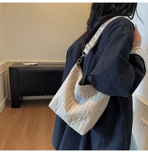Détail du sac plissé beige avec bandoulière ethnique et étiquette de mode brodée