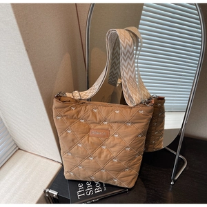Détail du sac cabas matelassé marron avec broderie nœud blanc et bandoulière tissée