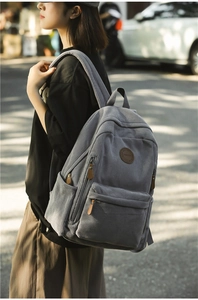 Detail of grey corduroy backpack with brown leather zip pullers and vintage label