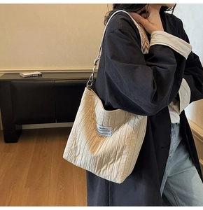 Gros plan d'un sac cabas matelassé beige avec étiquette mode et sangle tissée
