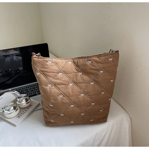 Détail d'un sac cabas marron matelassé avec broderies délicates de nœuds blancs