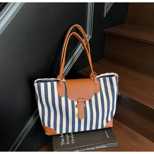 Detail of blue and white striped tote bag with brown faux leather handles and base