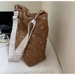 Détail du cabas matelassé marron avec broderie nœud blanc et bandoulière tissée