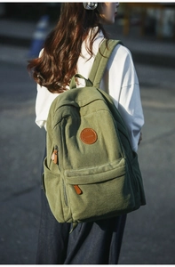 Detail of light green corduroy backpack showing soft texture and leather logo patch