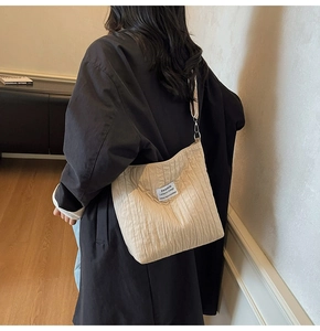 Détail du sac fourre-tout matelassé beige montrant la texture ondulée et le logo patch