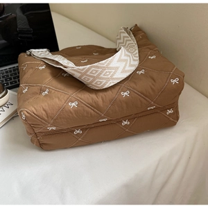 Gros plan du sac marron matelassé avec broderie nœud blanc et bandoulière tissée