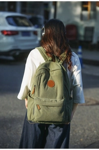 Detail view of olive green corduroy backpack with leather logo patch and zipper pulls