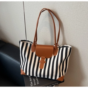 Detail of canvas tote bag with black and white stripes and brown leather handles