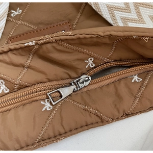 Gros plan sur un sac marron matelassé avec fermeture éclair et broderie de nœuds