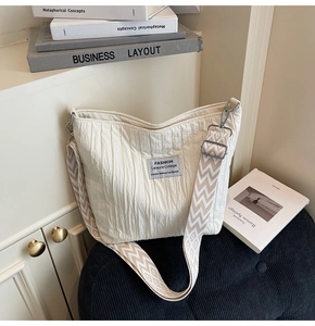 Détail d'un sac cabas matelassé blanc avec bandoulière à vagues sur siège bleu