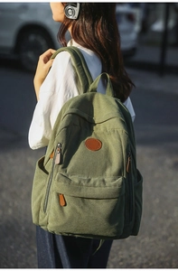 Close-up of dark green corduroy backpack showing fabric texture and leather logo detail