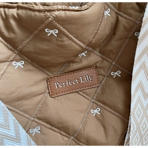 Détail macro du sac cabas matelassé avec broderie nœud et écusson en cuir Perfect Lily