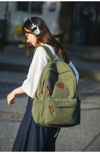 Detail of dark green corduroy backpack showing texture and leather zipper pulls