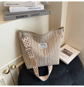 Détail du sac fourre-tout plissé beige avec bandoulière jacquard et étiquette carrée