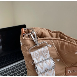 Détail du sac matelassé marron avec broderie de nœuds blancs et crochet en métal argenté