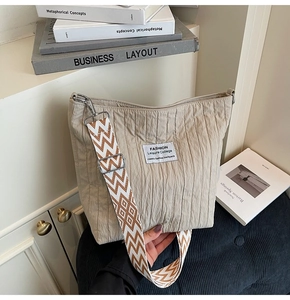 Détail du sac cabas en toile plissée beige avec étiquette mode et bandoulière tissée