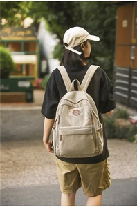 Outdoor shot of cream corduroy backpack highlighting detailed fabric texture and logo