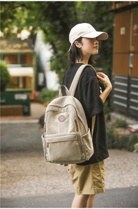 Detail of beige corduroy backpack showing textured fabric and side pockets in outdoor use