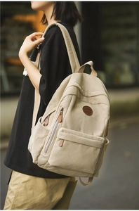 Detailed view of beige corduroy backpack texture with leather zip pulls and side pockets