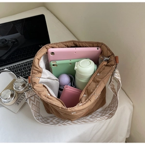 Vue détaillée de l'intérieur d'un grand sac fourre-tout matelassé marron avec tablette et accessoires