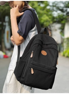 Close-up of black corduroy backpack showing vertical texture and brown leather patch detail