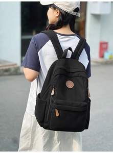 Detailed view of black corduroy backpack showing durable texture and side storage pocket