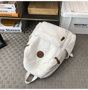 Close-up of white corduroy backpack texture with round brown leather logo patch