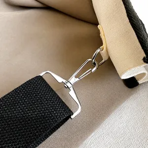 Detail der silbernen Hummer-Schließe und des schwarzen gewebten Gurtes der Canvas-Tasche