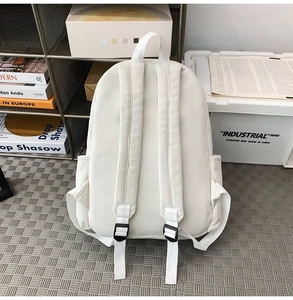 Detail view of white corduroy backpack straps and side pocket in industrial studio