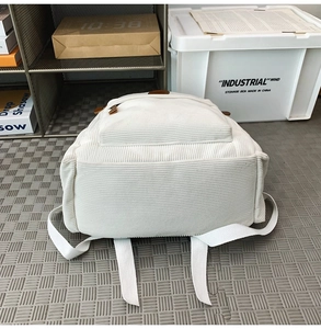 Detailed bottom view of white corduroy backpack showing durable stitching and soft texture