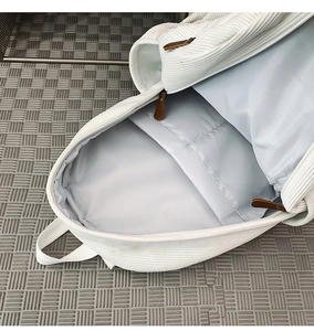 Detail view of corduroy backpack interior featuring a large main compartment and zipper pocket