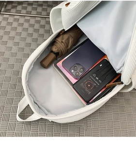 Detailed interior of a white corduroy backpack showing large capacity and storage space