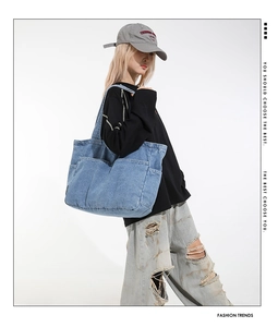 Detail of light blue denim tote bag with two large functional front pockets and washed texture