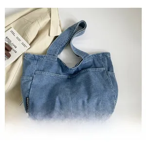 Detail showing the spacious denim tote bag with wide strap and large front pocket