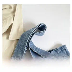 Close-up of reinforced denim tote bag handles with durable stitching on light blue fabric