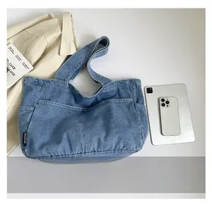 Macro view of blue denim tote bag showing side woven label and washed fabric texture