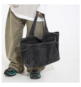 Detail showing the exterior pockets and brand label on this large charcoal denim tote bag