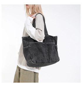 Detail of black washed denim tote bag showing side functional pocket and fabric texture