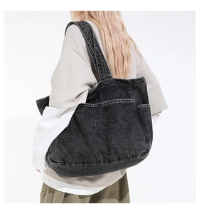 Close-up of black denim tote bag with multiple pockets worn by a female model
