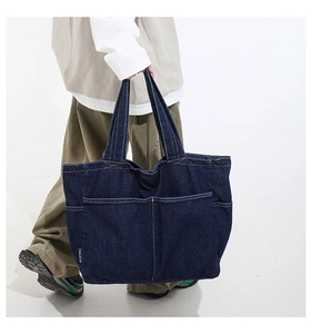 Macro detail of large capacity denim tote bag showing multi-pockets and fabric texture