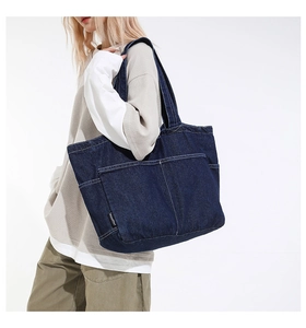 Detail of dark blue denim tote bag showing side pockets and reinforced stitching