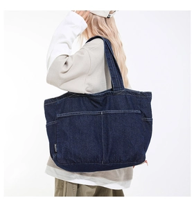 Close-up of deep blue denim tote bag with white stitching and multi-pocket design details